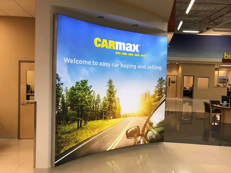 CarMax brand wall slogan on a lightbox fabric with an open road image in the mountains.